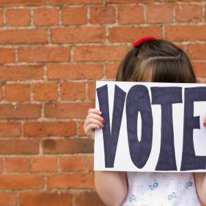 School child holding a 'Vote' sign