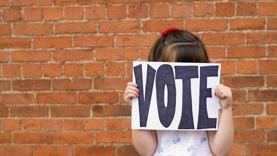 School child holding a 'Vote' sign