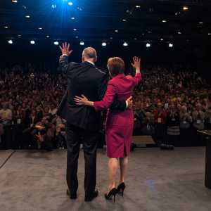 The First Minister of Scotland, Nicola Sturgeon, with Deputy First Minister, John Swinney, waving to the crowd at the 2015 SNP Conference.