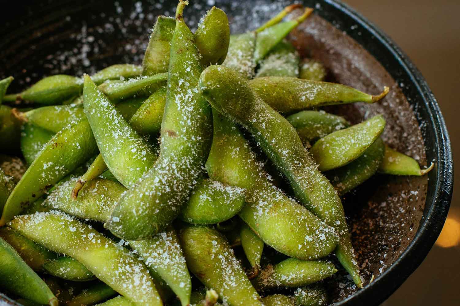 edamame beans in a black bowl with salt