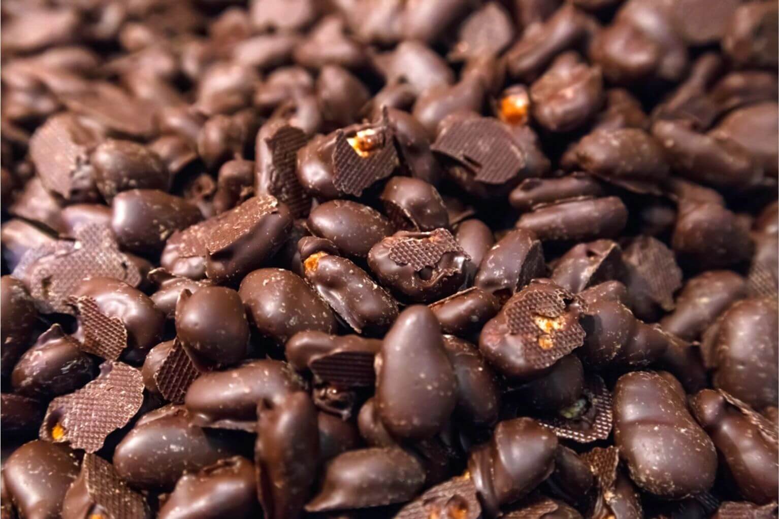Dark chocolate covered almonds in a pile.