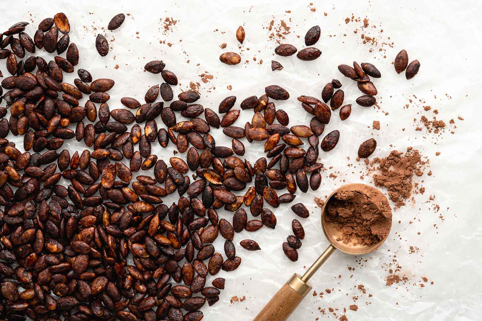 Cocoa roasted pumpkin seeds on counter with extra powder on spoon