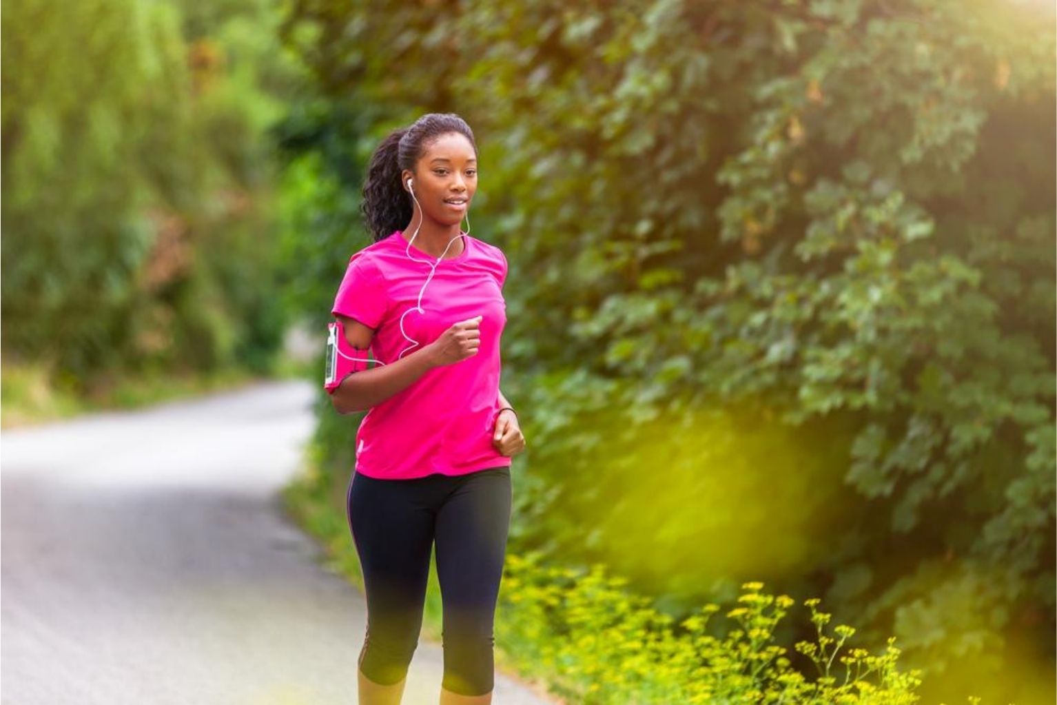 Woman in a bright pink shirt running along an outdoor trail