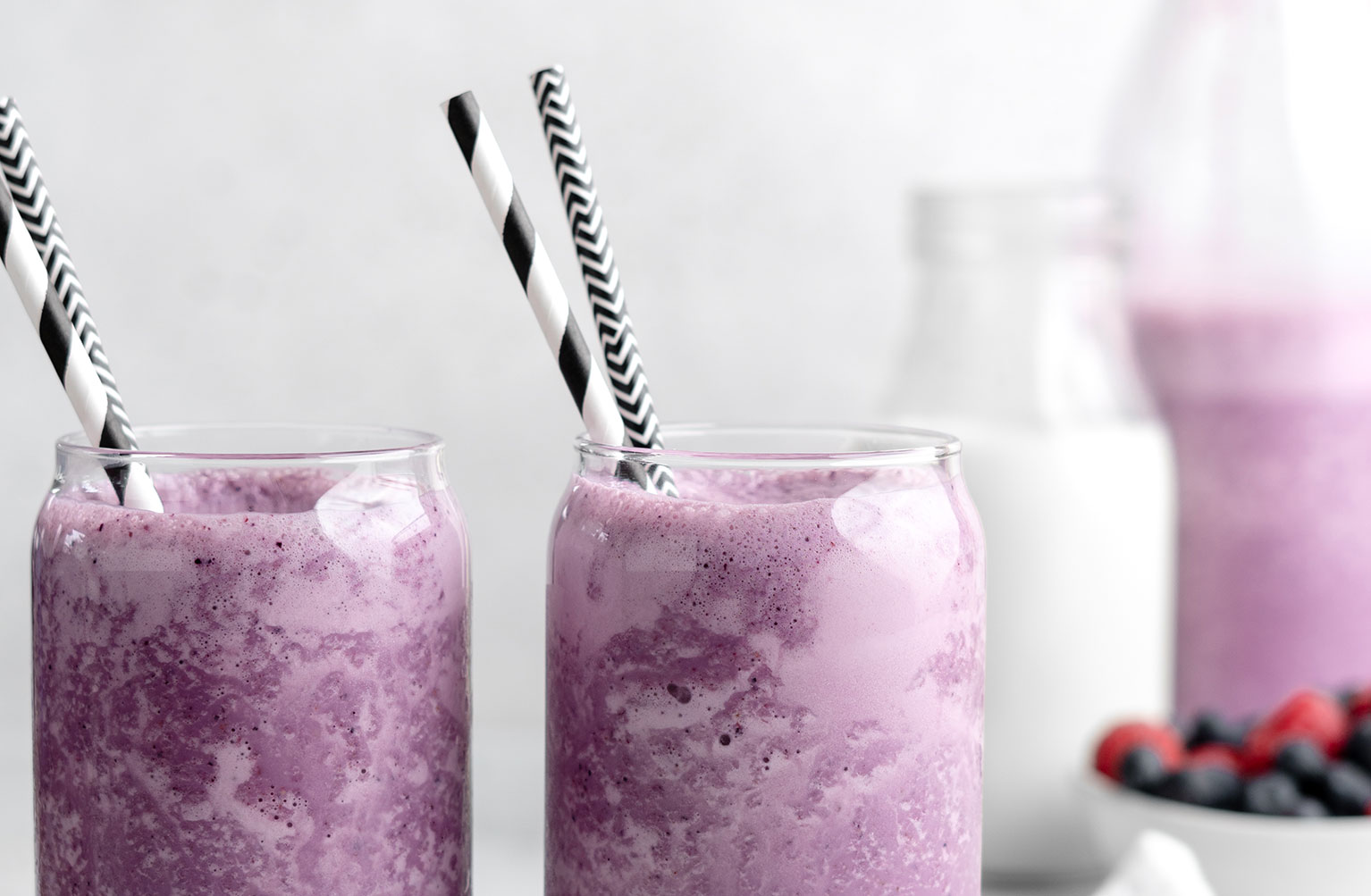 Two roasted berry milkshakes in glasses with straws