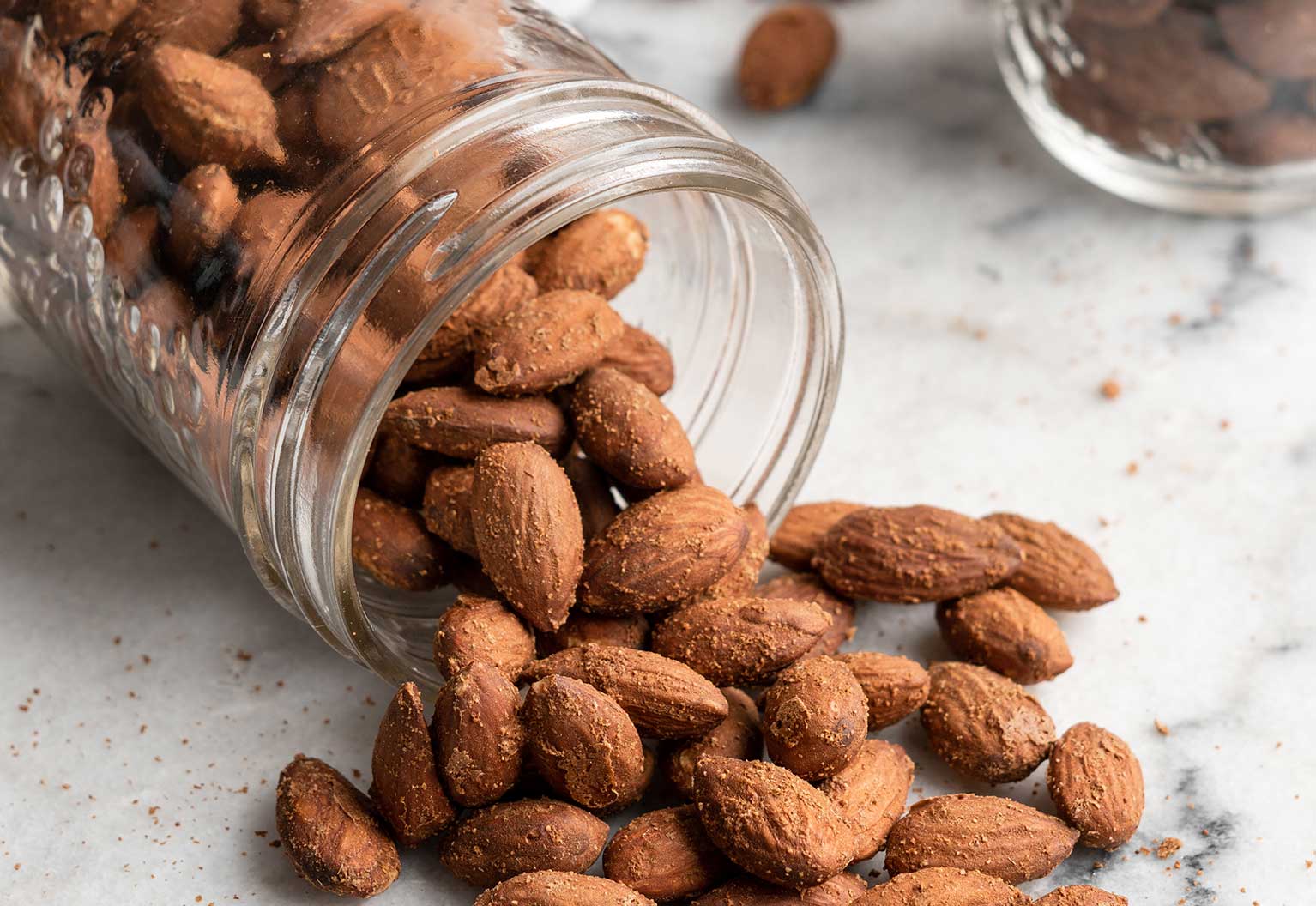 Savory almonds roasted with ginger and garlic spilling out of a jar