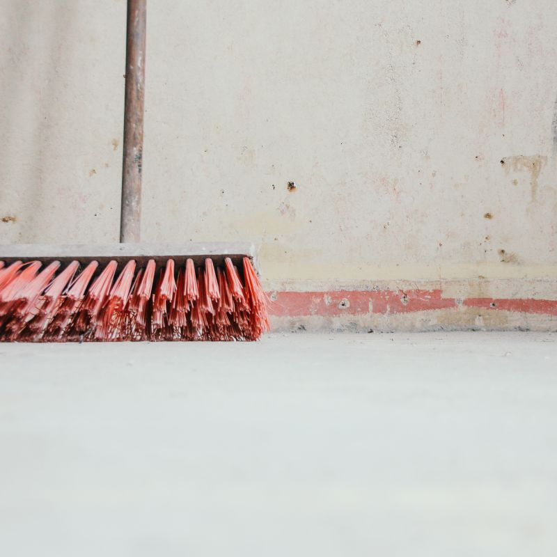 Ein Besen mit roten Borsten lehnt an einer Wand. Wir übernehmen neben Hausmeisterleistungen noch weitere Bereiche der Hausverwaltung, in Zusammenarbeit mit erfahrenen Partnern.