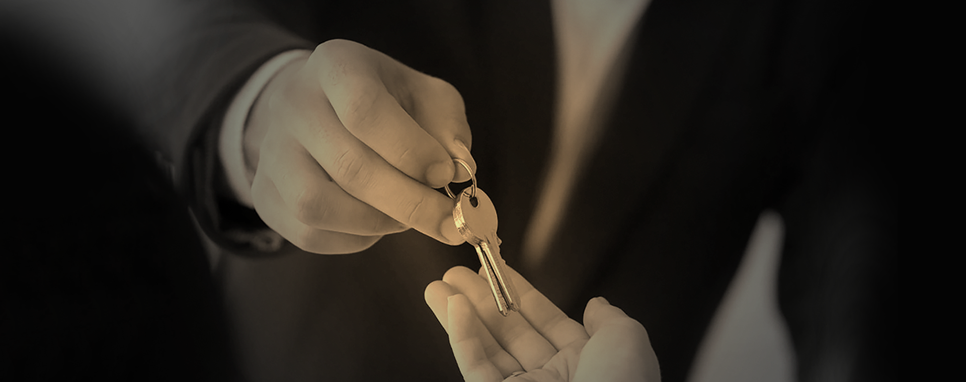 Man in suit handing building keys to another person