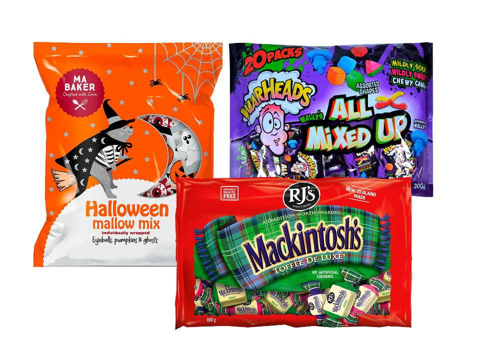 Three bags of assorted Halloween candy arranged together: an orange bag of Ma Baker Halloween Mallow Mix featuring a bear on a broomstick, a purple bag of WarHeads All Mixed Up chewy candy, and a red bag of RJ's Mackintosh's Toffee De Luxe.