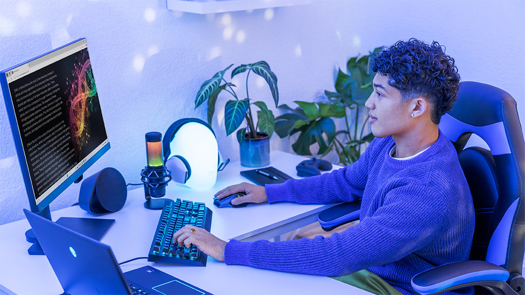 A man sits at his external monitor in a gaming chair