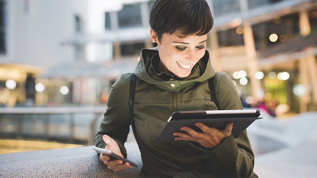 A woman using a tablet and a smart phone to write a message with the aid of Copilot