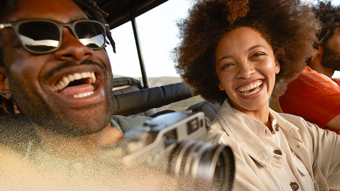 A cheerful young couple sitting with a camera at a national park during sunset