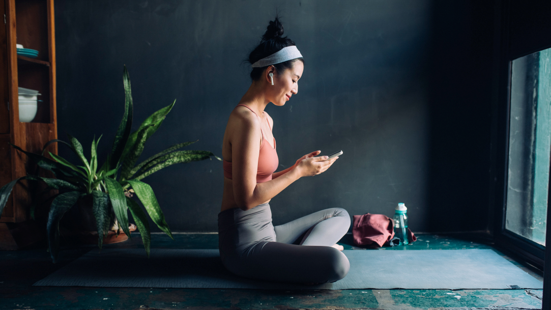 A young woman on a yoga mat checking her phone