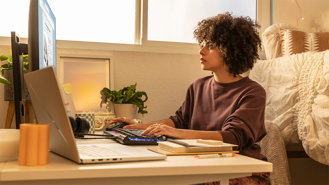 A college student studying on their computer in their dorm room