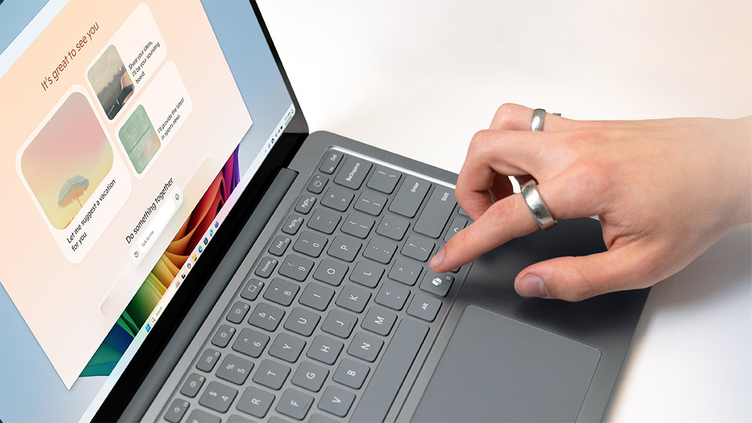 A person presses a key on a Surface laptop with Copilot’s UI on the screen