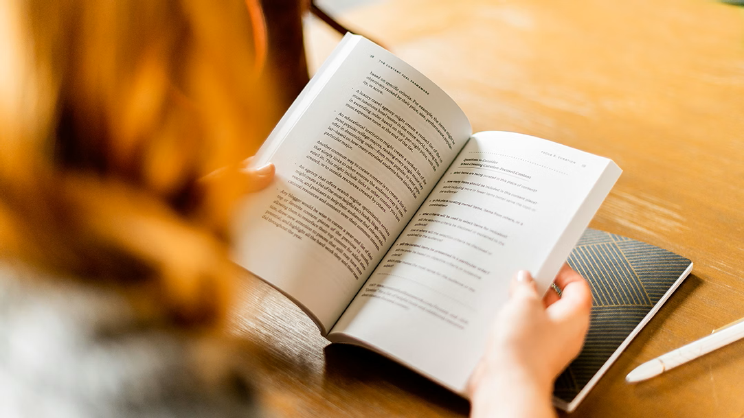 Person preparing for book discussions reading book at a brown wooden table
