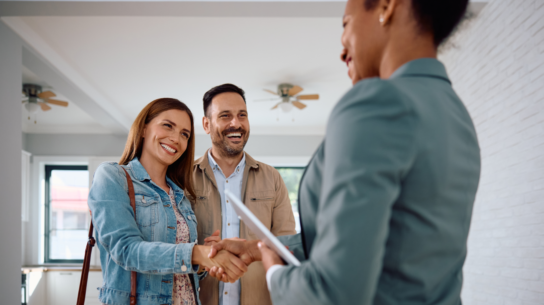 A real estate agent shaking hands with buyers of a new home