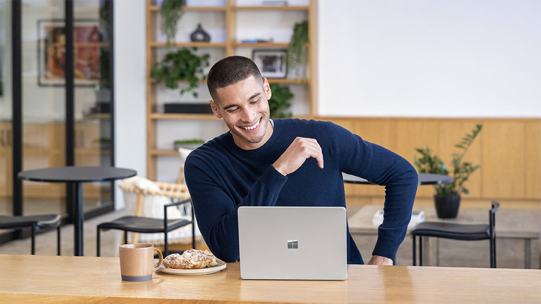 A man smiling at the counter of a café while using an AI email assistant to clear his inbox