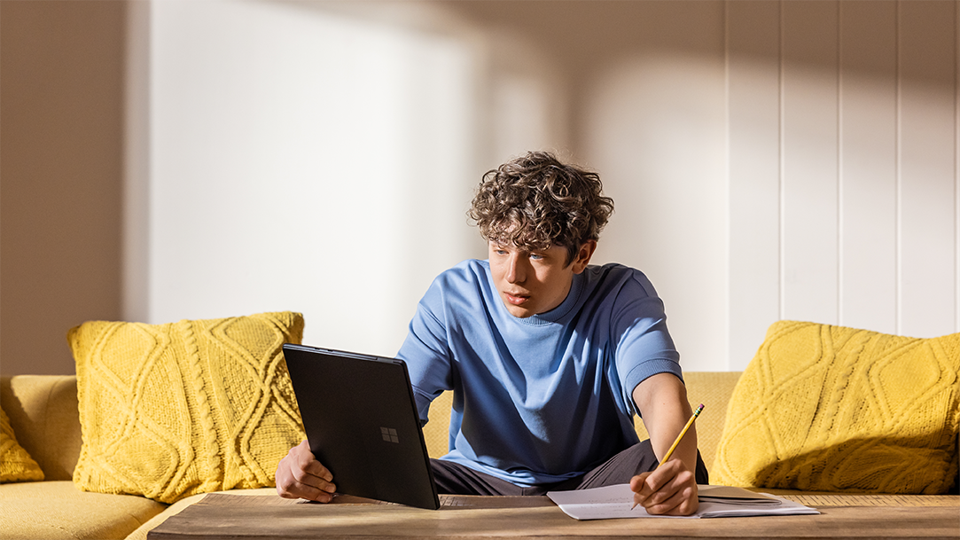 Student focused on their writing homework in a brightly lit living room
