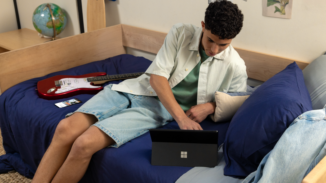 A college student looking up guitar chords on his computer with Copilot