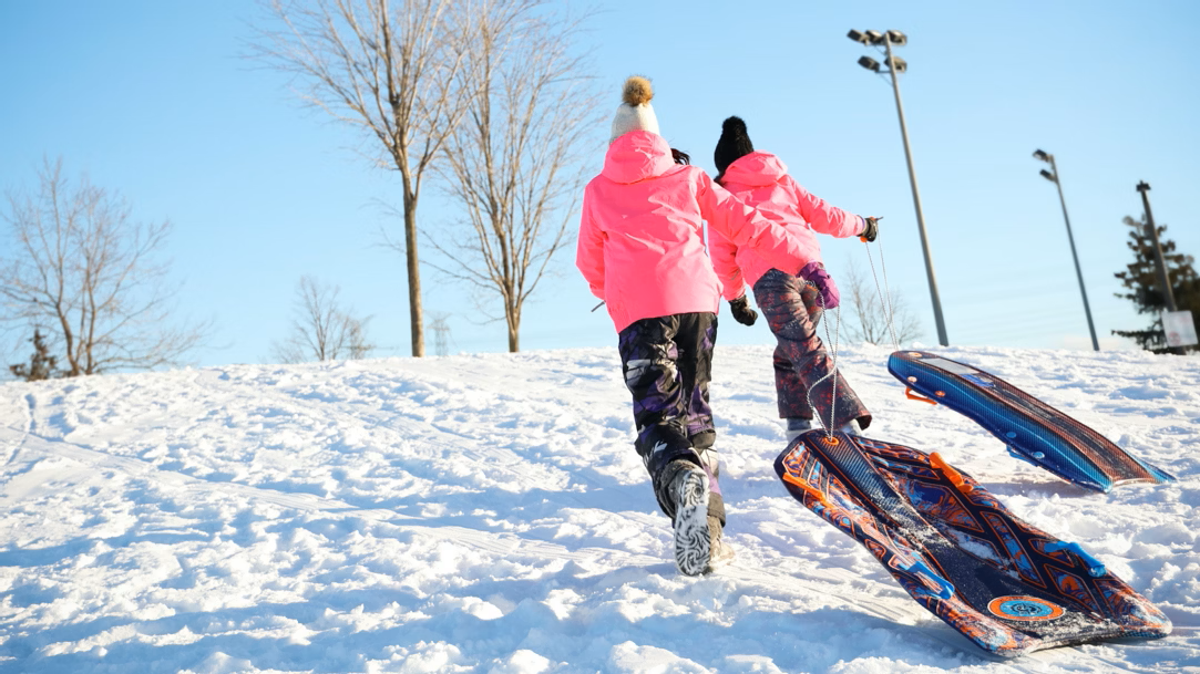 Kids pulling sleds up a snow-covered hill