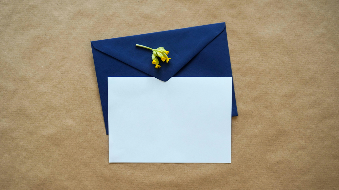 A top-down view of a blank invite card and a dark blue envelope on a plain background