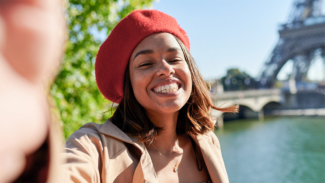 A happy person on vacation in Paris taking a selfie in front of the Eiffel tower