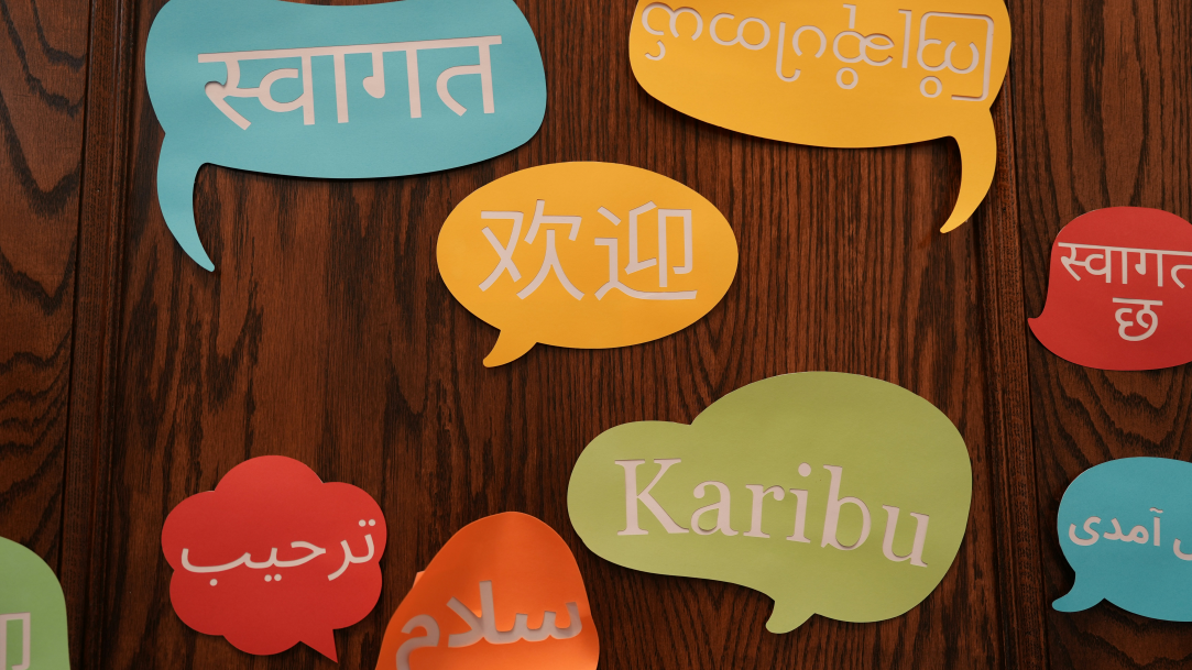 Colorful paper speech bubbles with text in different languages on a wooden wall