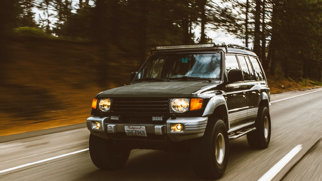 A green SUV driving on a road