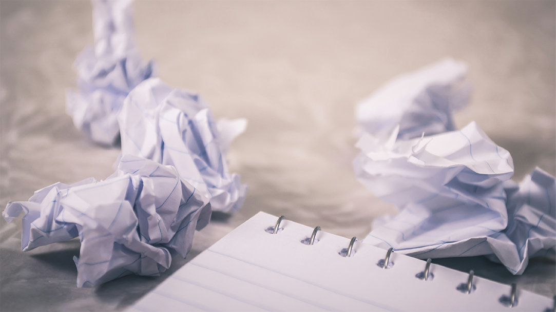 Crumpled white notebook paper on a brown table 
