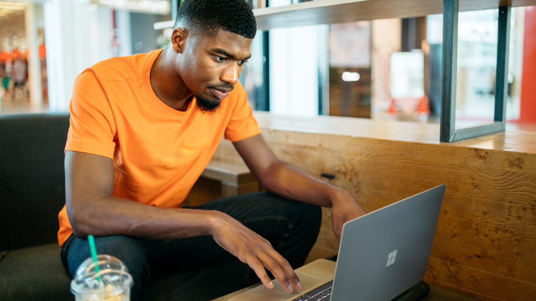 A college student using AI to write code on a Surface Laptop in a study hall