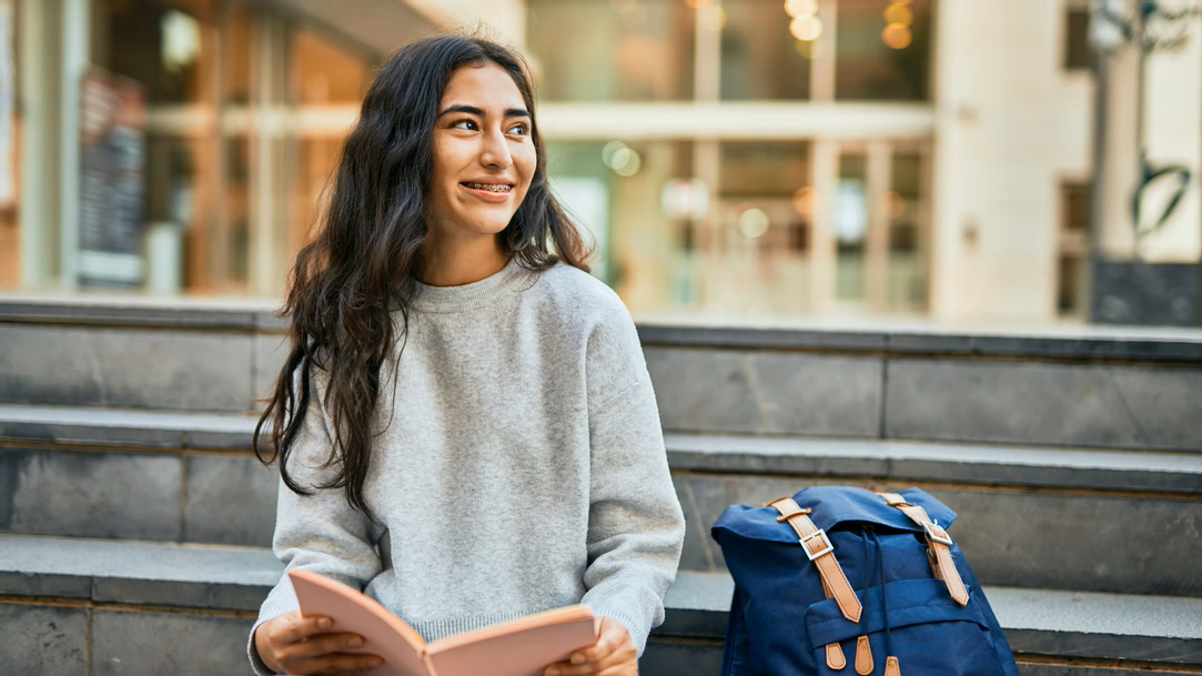 A student smiling reading a book at a university