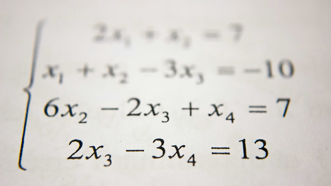 Math homework showing a system of printed equations on a paper