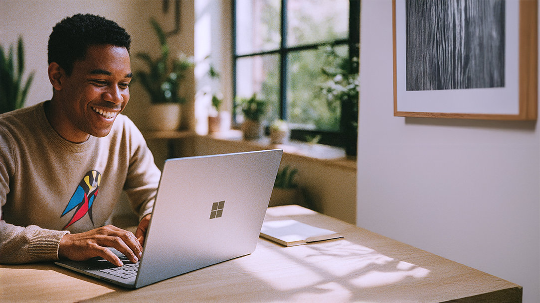 A happy person typing prompts into Copilot on their Surface laptop