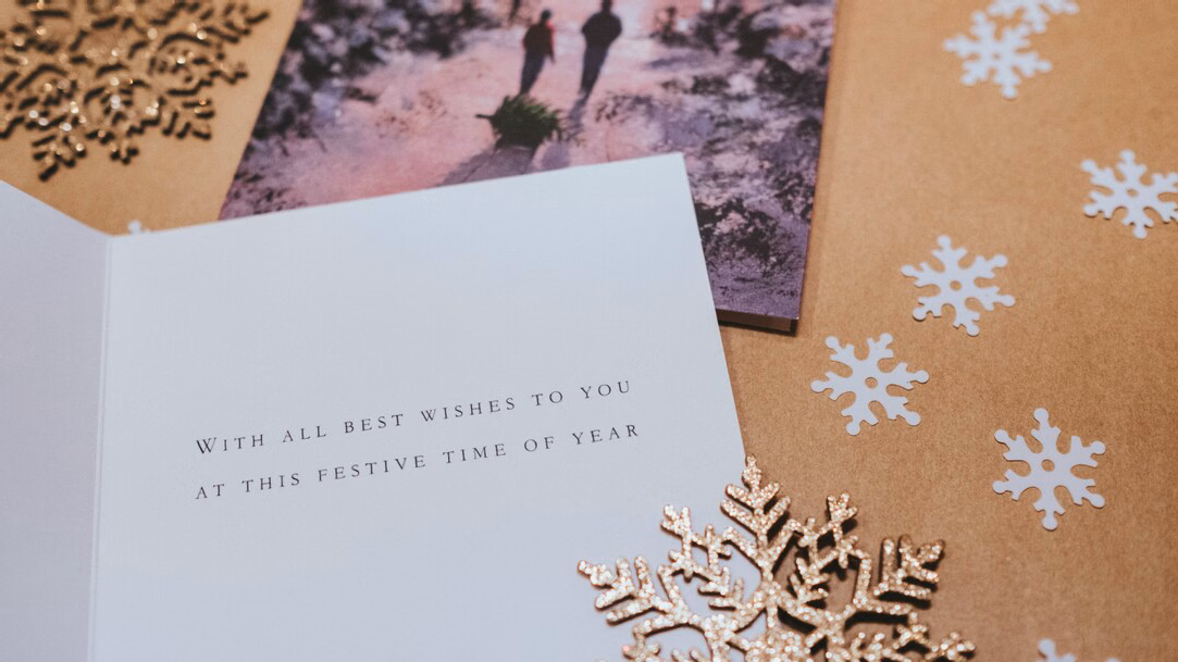 A white greeting card on a brown background and cut out paper snowflakes