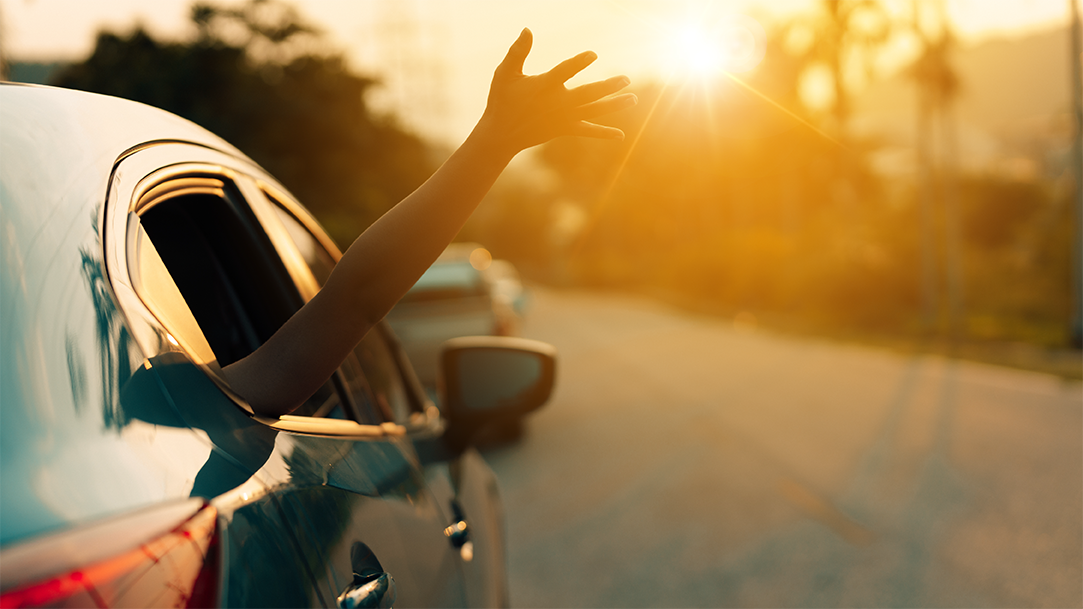 A carful of people on a road trip adventure into the sunset