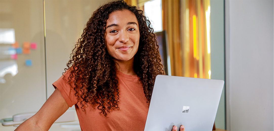Smiling female entrepreneur with laptop standing in office