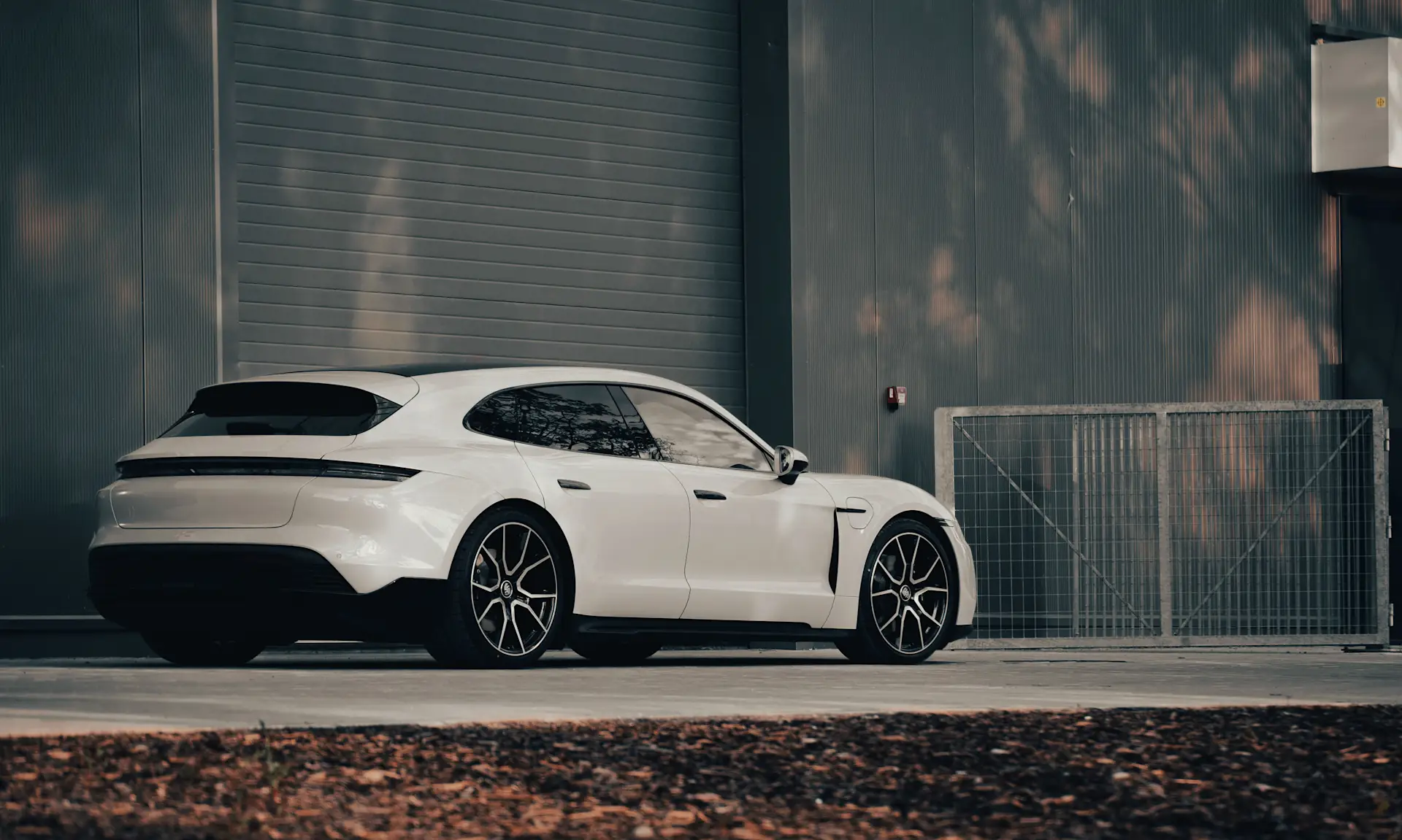 Auto järven rannalla mökillä auringonlaskun aikaan, mäntyjen lomasta siivilöityy kultainen valo veden pinnalle.