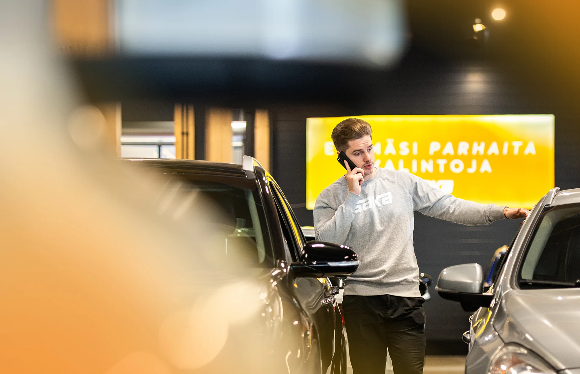 Henkilö puhuu puhelimeen autoliikkeessä.