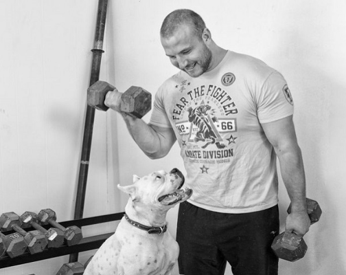 Lilly, a white bulldog pictured with Craig curling dumbells
