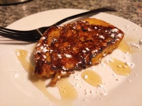 French toast on a white plate with syrup and powdered sugar