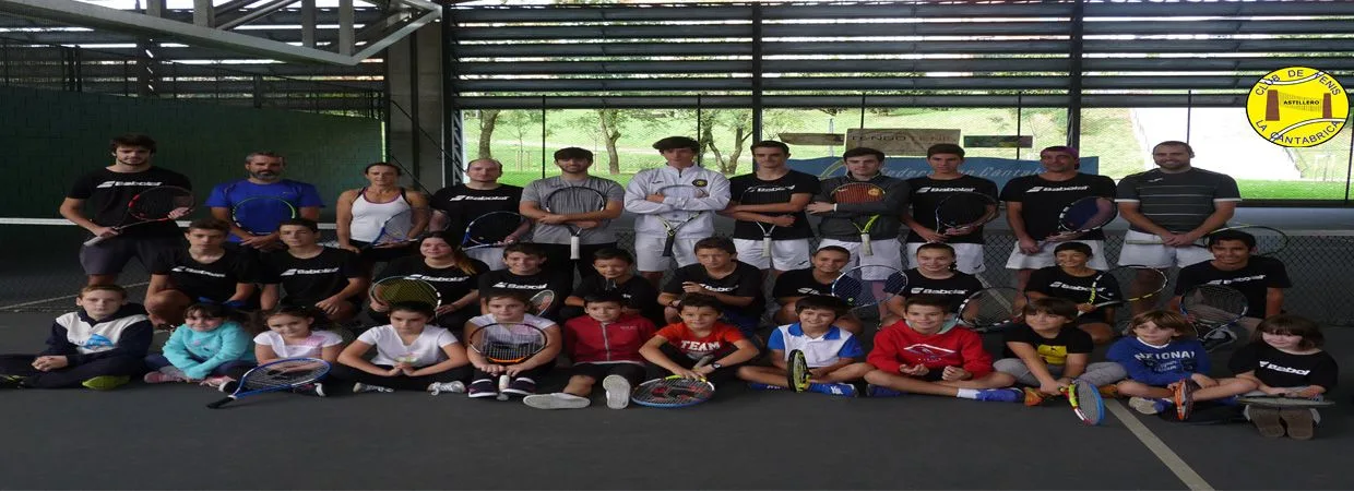 Jugadores de distintas edades posan con sus raquetas en la pista cubierta.