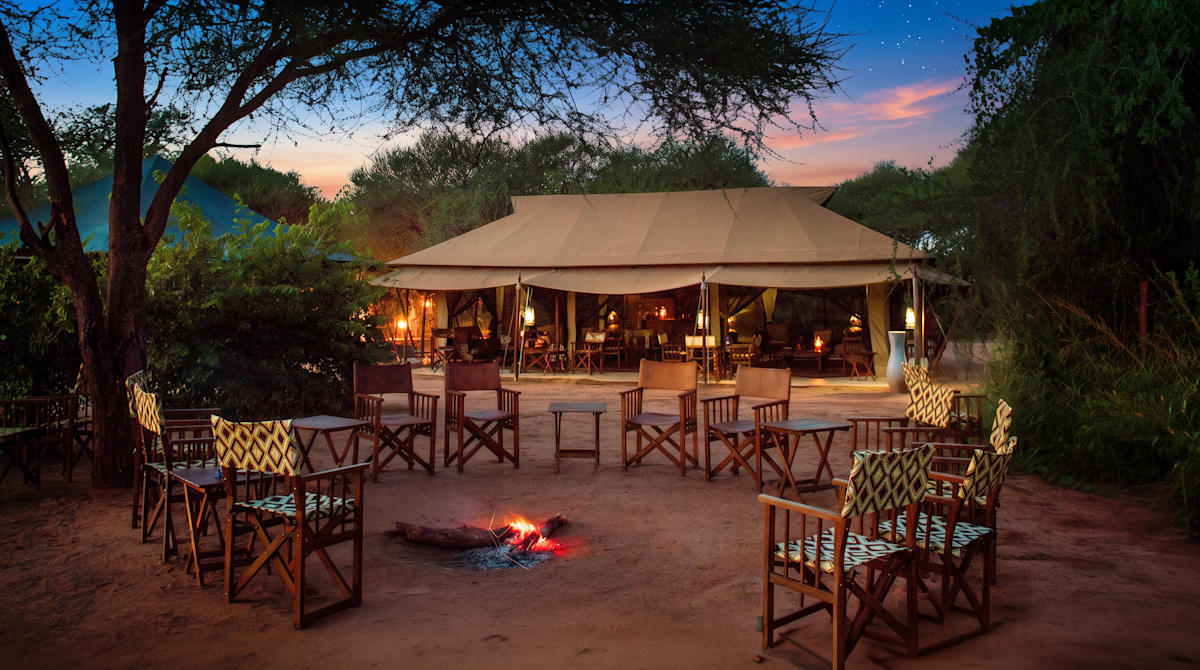 Campfire circle with director's chairs in front of the lounge tent at dusk at Tarangire Nyumba