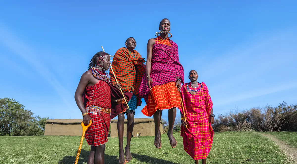 Maasai men and women in red shukas jumping during a traditional dance in the Eastern Serengeti