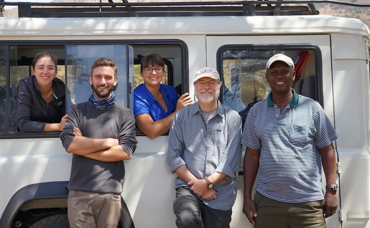 Thomson travelers and their local guide leaning against a safari vehicle