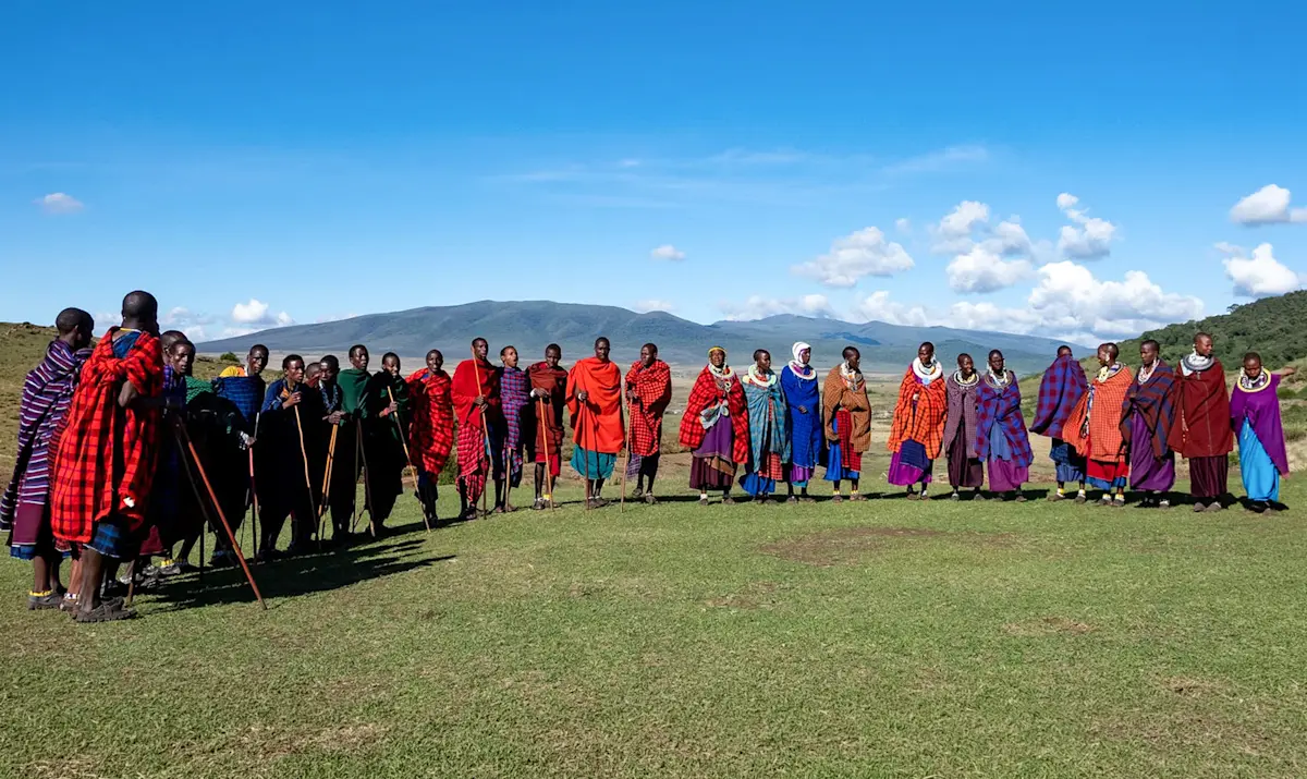 Line of Maasai men and women in colorful shukas during a boma visit in the Ngorongoro Highlands