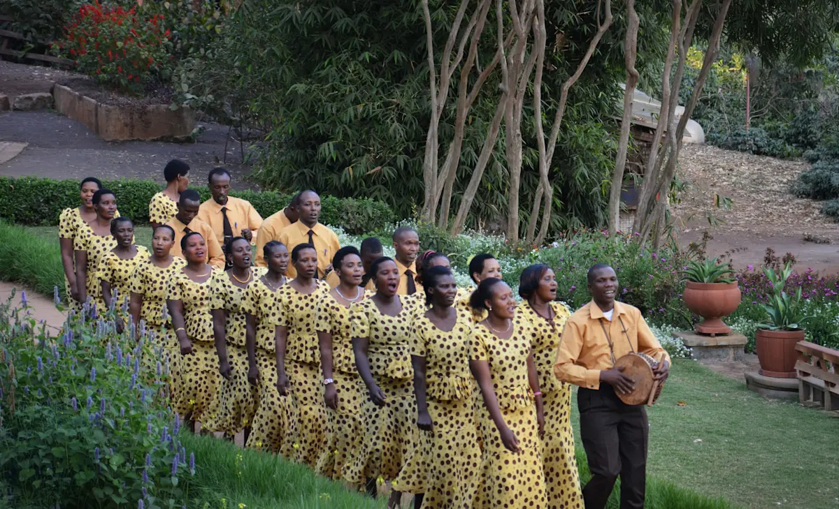 Choir in yellow patterned outfits singing in the garden at Gibb's Farm