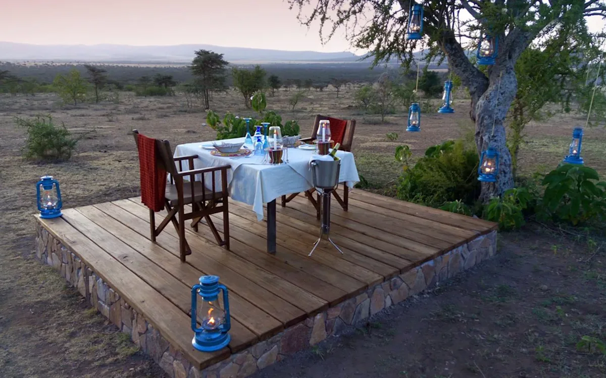Table set for dinner on a wooden deck lit by lanterns at Eastern Serengeti Nyumba