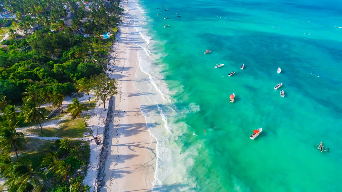 Aerial view of a white sand beach, turquoise water and small boats off Zanzibar