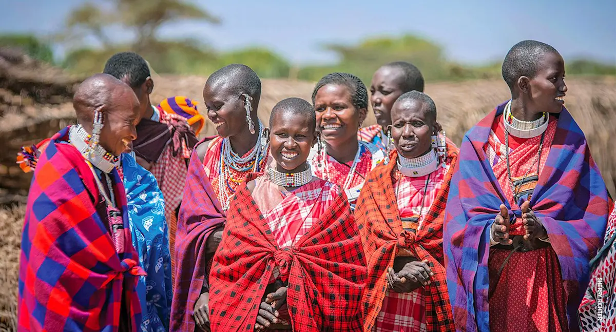 Group of smiling Maasai women in colorful shukas and beaded jewelry