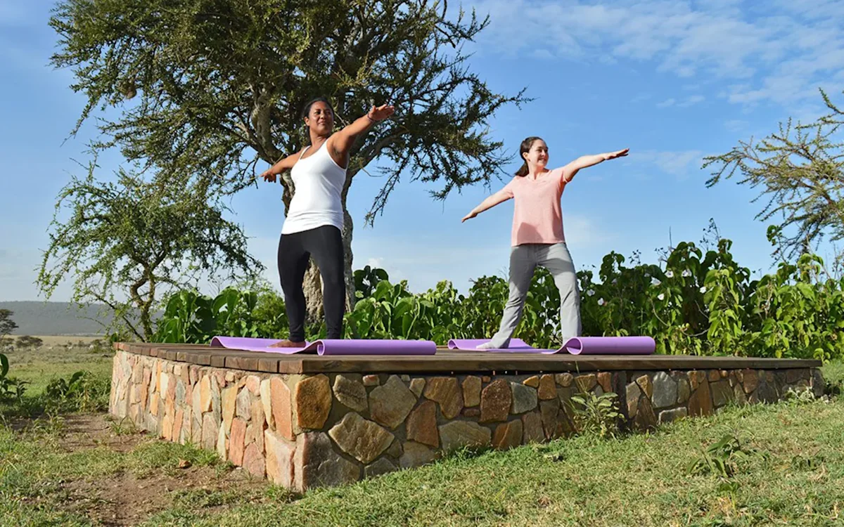 Two guests doing yoga on a stone platform at Eastern Serengeti Nyumba